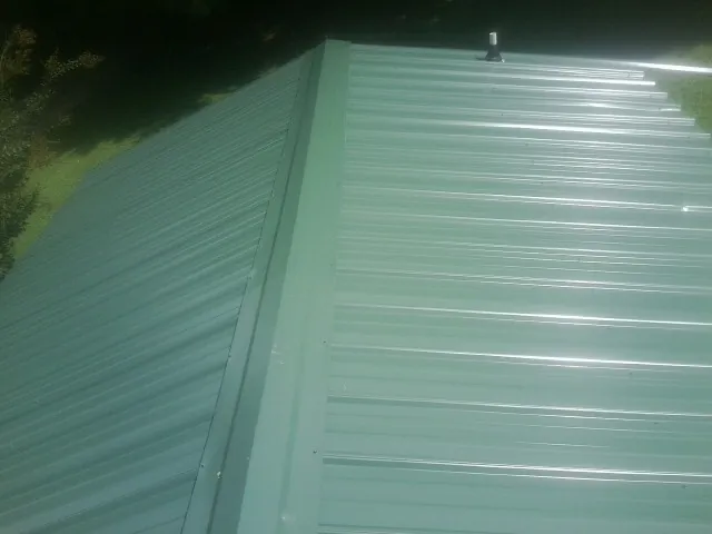 New green metal panels meeting at the ridge of a roof — Flat Roof Repair work by our crew in Elberta