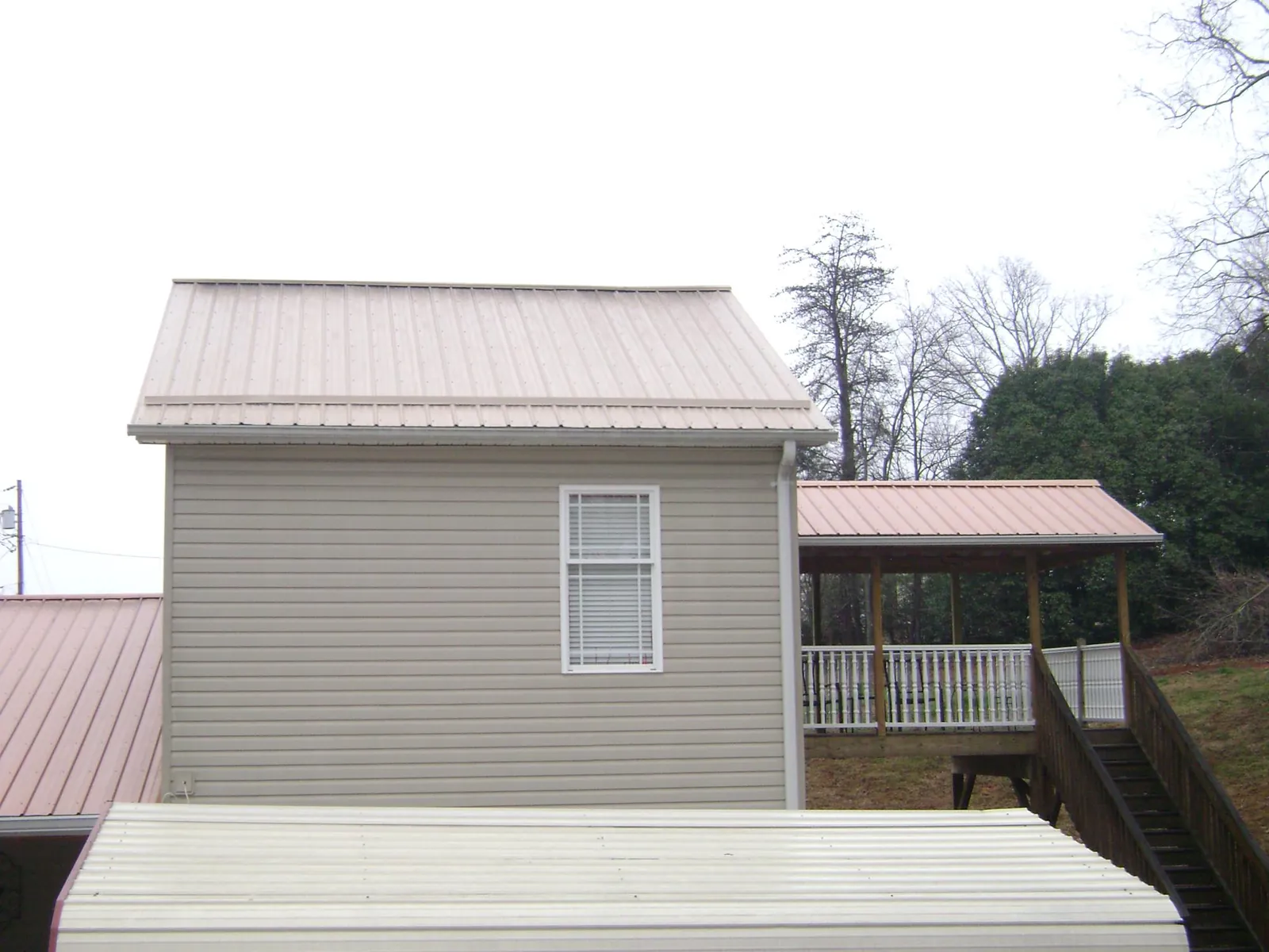 Tan metal roofs on a two story addition and attached porch, from a Roof Replacement job in Elberta