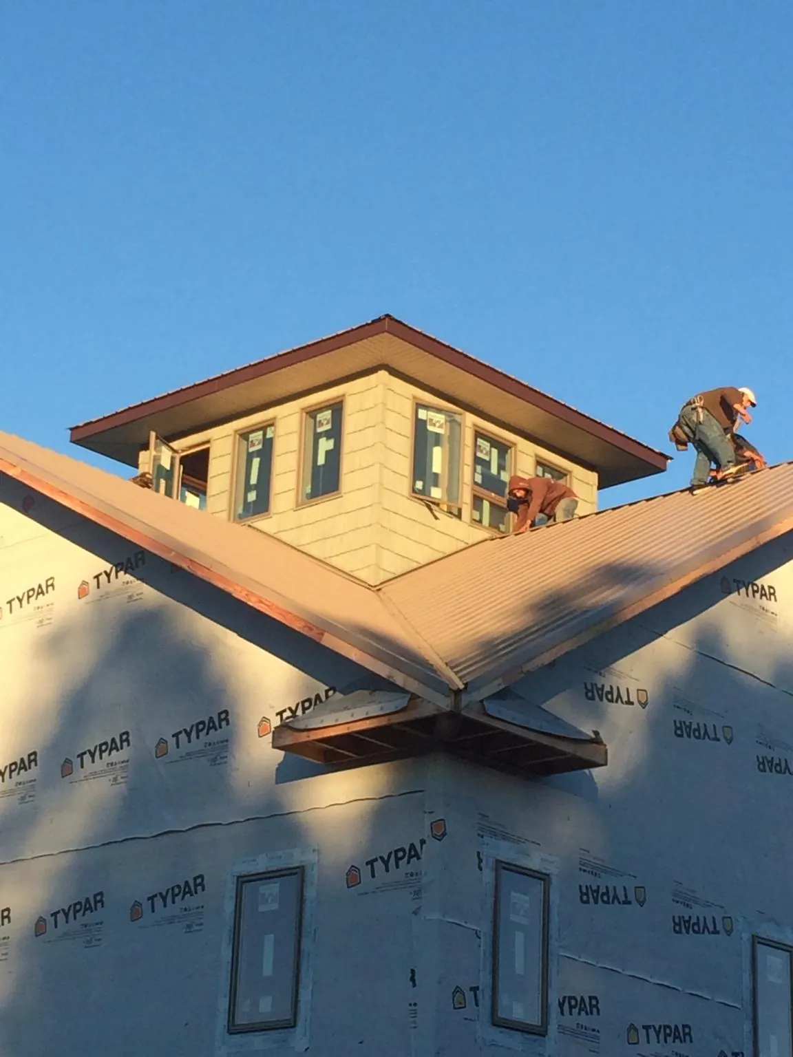 Roofers working around a rooftop cupola on a new metal roof at sunset — Roof Waterproofing in Elberta by Roofing Brothers